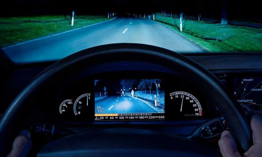 Imagen de cerca y de frente del volante de un coche donde tiene instalada la cámara nocturna y al fondo se ve la carretera oscura.