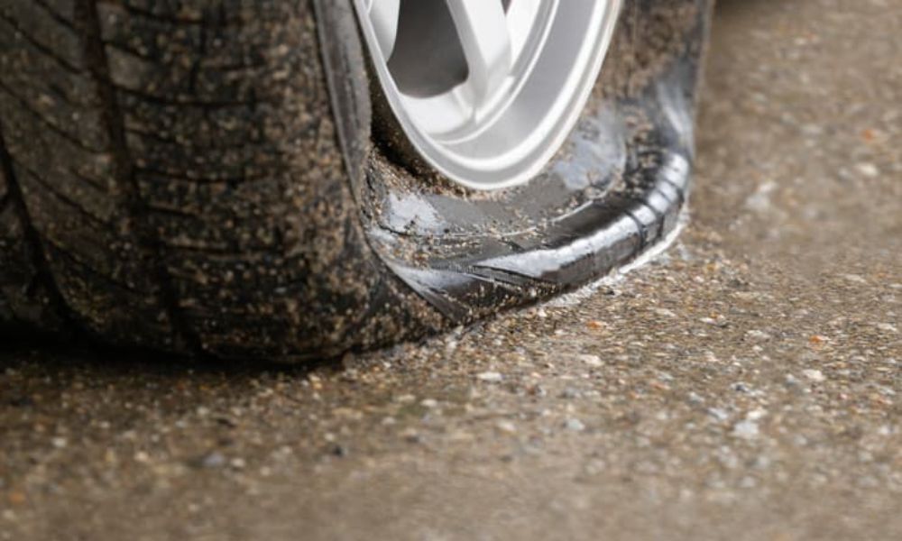 Imagen de un primerísimo primer plano de la parte inferior de un neumático de coche pinchado en el asfalto de la carretera | Mycaready Technologies