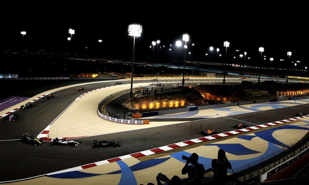 Fotografía en la que aparece una parte del recorrido del circuito de Fórmula 1 de Bahréin, de noche y los pilotos compitiendo por el Gran Premio.