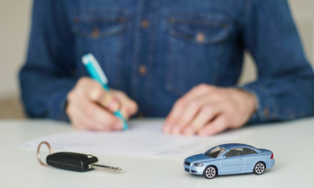 Joven conductor firmando su contrato de compra financiada de coche, luego de haber pasado todos los requisitos para la compra del coche.