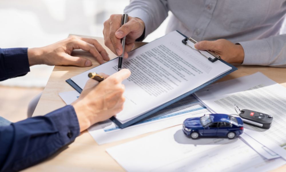 Vendedor de coches muestra documento para la solicitud de ayuda para comprar coche en el 2023 a un hombre interesado en coches eléctricos.