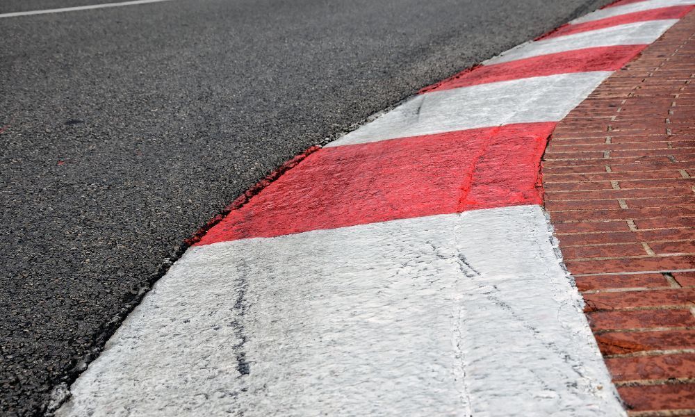 Foto de un circuito del Gran Premio de la Fórmula 1, con detalle en la calzada y el borde color blanco y rojo de la parte interna de la pista.