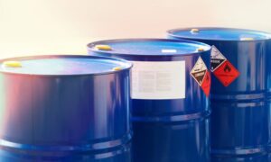 Imagen de cerca de tres bidones azules homologados para gestionar residuos peligrosos e inflamables siguiendo la normativa legal en un taller mecánico.