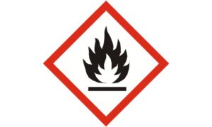 Imagen de una señal de advertencia vertical de un taller mecánico con forma rombo y de color rojo, blanco y negro, que indica el peligro de materiales inflamables.