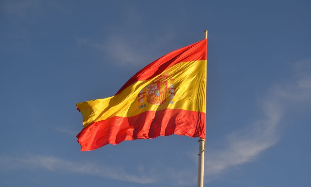 Detalle de la Bandera de España ondeando desde el parking de un camping de playa en una localidad española con todos los servicios para caravaning.