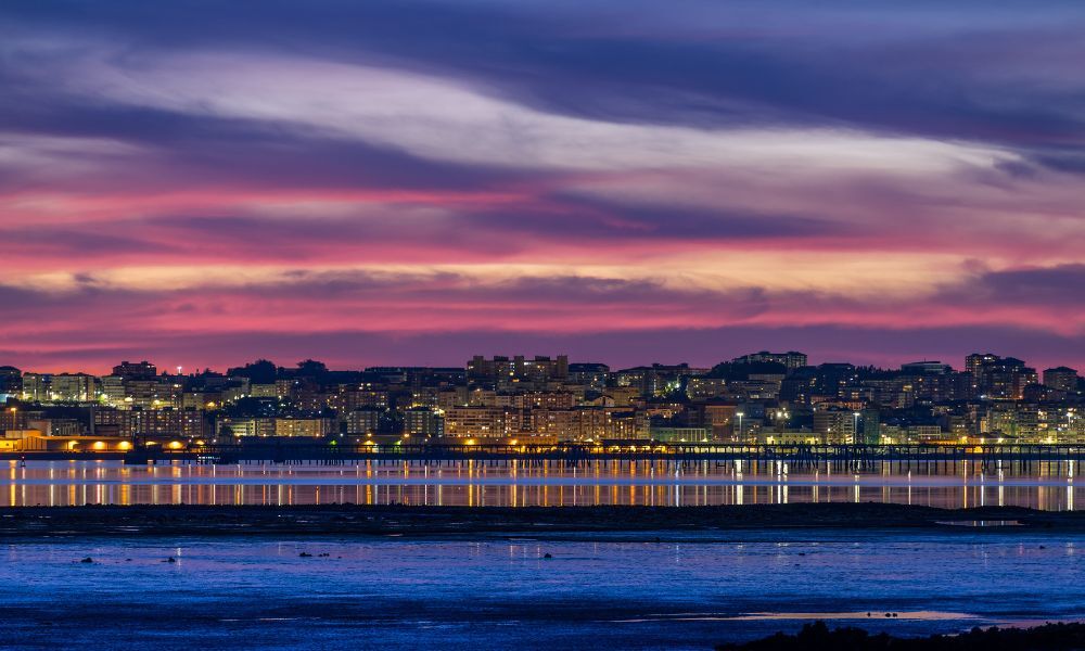 Atardecer urbano de la ciudad de Santander al norte de España, desde la playa se ve el paisaje urbano con sus edificaciones y luces encendidas.
