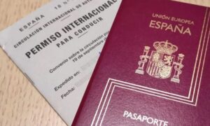 Detalle de un permiso de conducir internacional emitido en España acompañado por un pasaporte español sobre una mesa de color marrón claro.